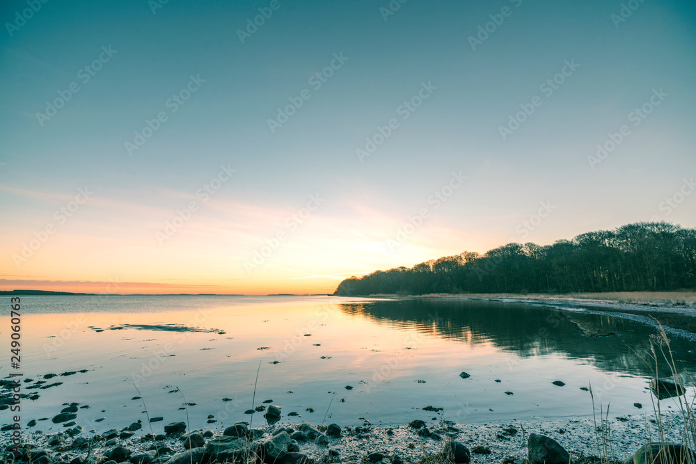 Lake in the sunrise with rocks on the beach