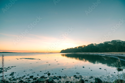 Lake in the sunrise with rocks on the beach