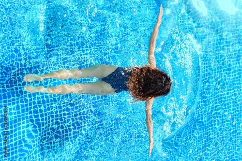 Woman swimming in pool, swim in breaststroke style, with arms wide apart. Top view. Straight body, slim. Swim and fitness concept.