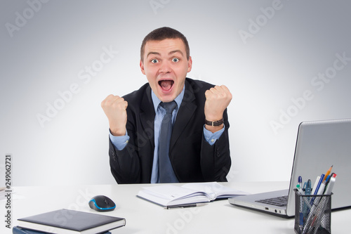 Smiling businessman with laptop computer and documents at office