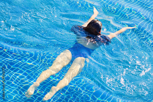 Top view of woman swimming in a pool. Straight body  slim woman. Swim and fitness concept.