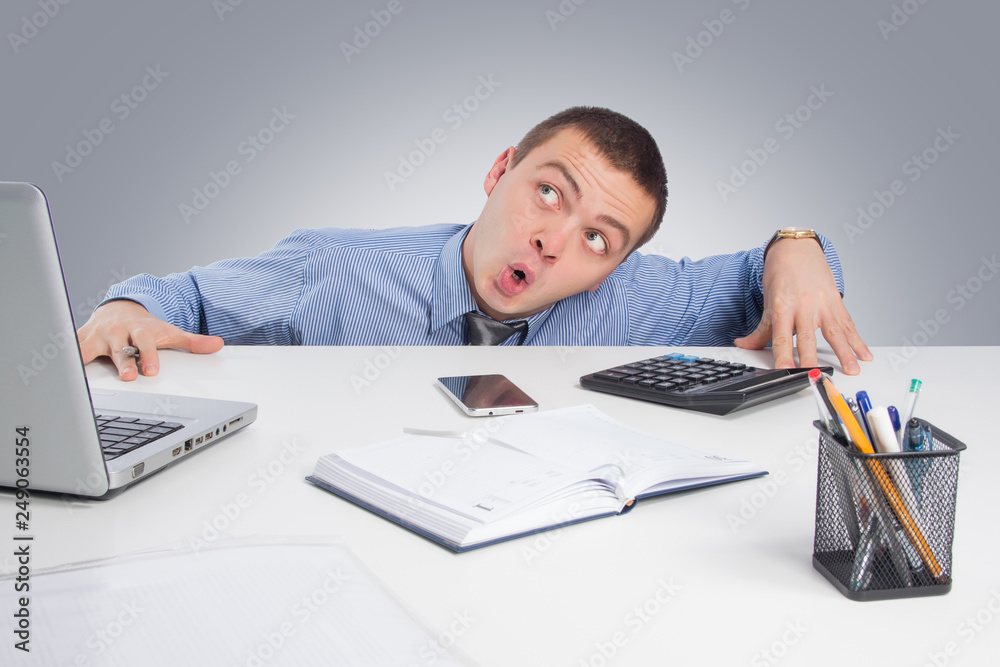 Shocked businessman with laptop computer and documents at office on gray background