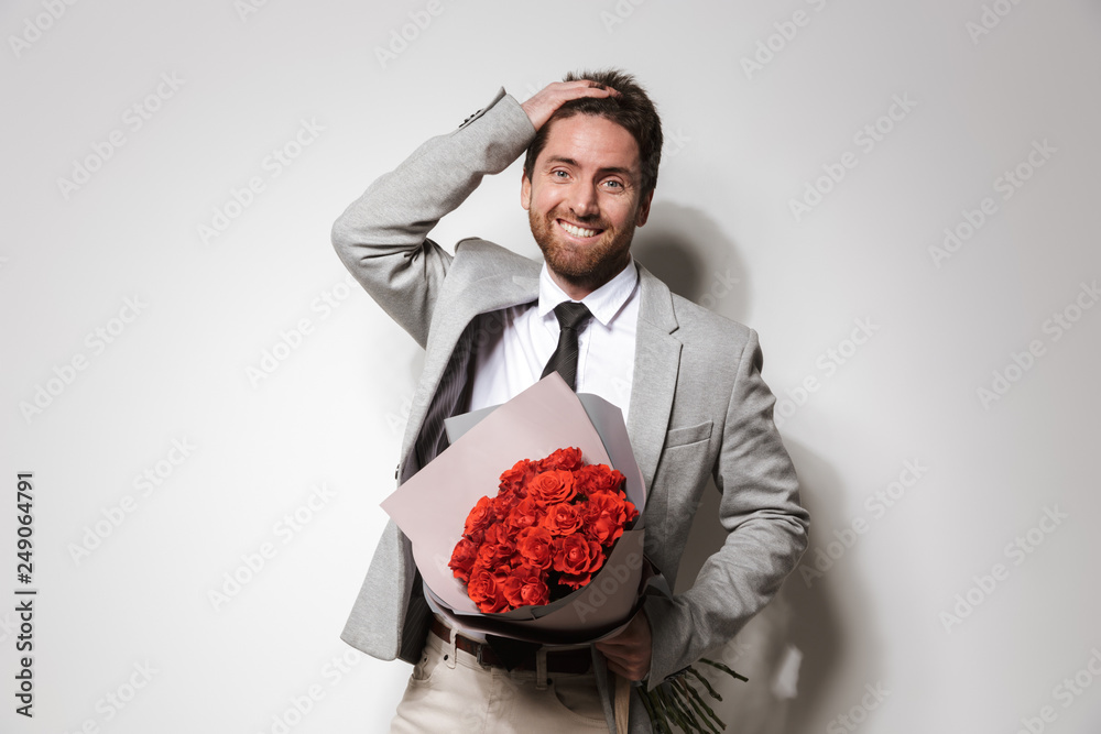 Businessman in formal clothes isolated over white wall background holding flowers. Businessman in formal clothes isolated over white wall background holding flowers.