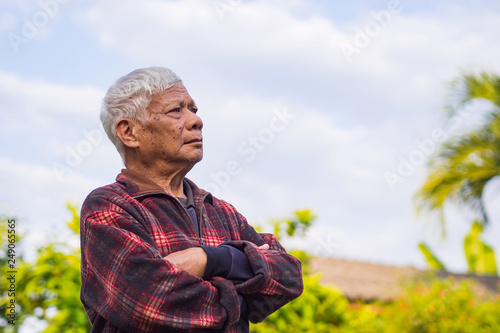 Portrait of elderly man standing and looking up in his garden.