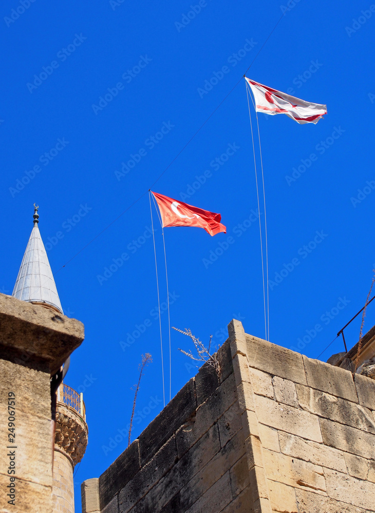turkish and north cyprus flying over Selimiye Mosque formerly the cathedral of Saint Sophia in nicosia cyprus against a blue sky