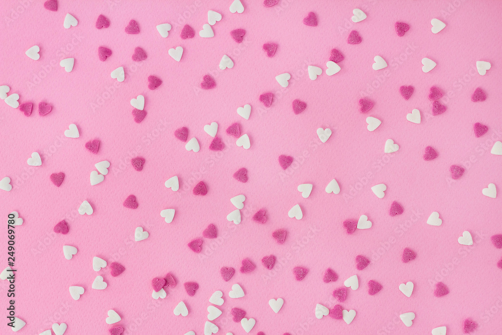 Candy sweets sugar sprinkle decoration in shape of heart on a pink background for wallpaper, card, invitation or poster