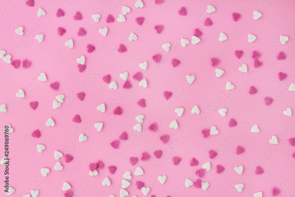 Candy sweets sugar sprinkle decoration in shape of heart on a pink background for wallpaper, card, invitation or poster Candy sweets sugar sprinkle decoration in shape of heart on a pink background for wallpaper, card, invitation or poster