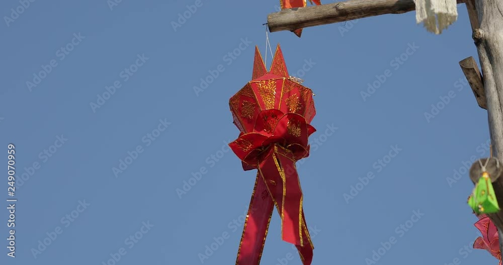 Colourful Northern Thai style paper lantern hanging on the wood pole with wind blowing.
