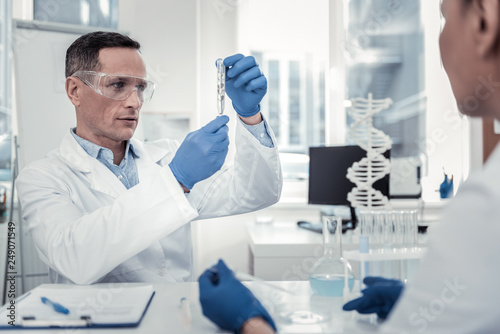 Concentrated biologist looking on the content of the test tube