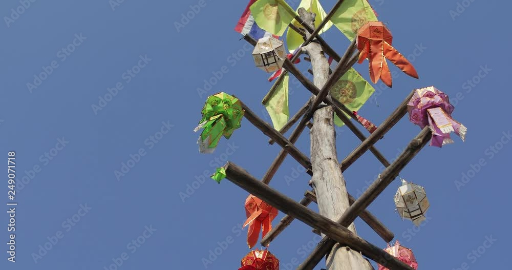 Colourful Northern Thai style paper lantern hanging on the wood pole with wind blowing.
