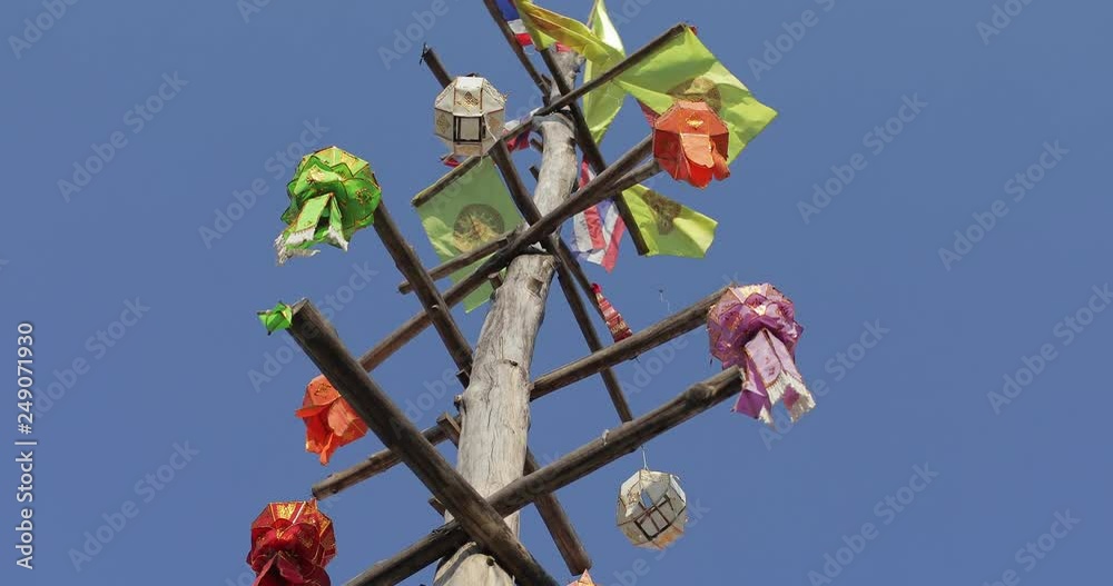Colourful Northern Thai style paper lantern hanging on the wood pole with wind blowing.