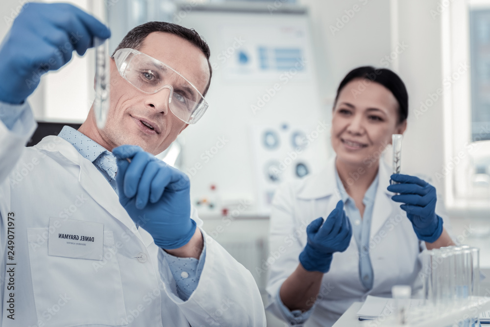Scientist showing the content of test tube to his colleague Scientist showing the content of test tube to his colleague
