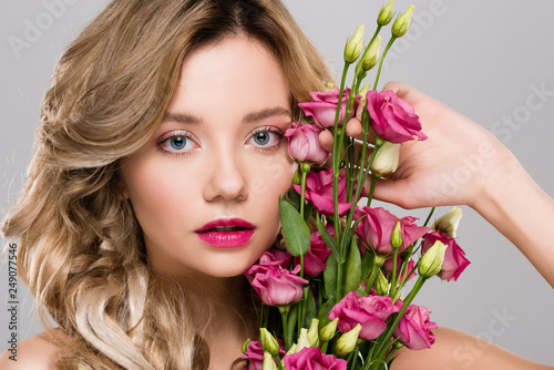 beautiful woman posing with spring Eustoma flowers bouquet isolated on grey