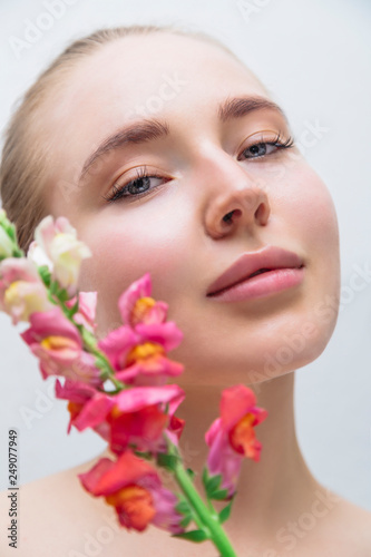 Beautiful girl s face with color flower near
