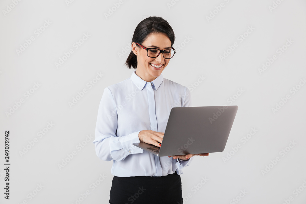 Portrait of businesslike woman wearing eyeglasses holding silver laptop in the office, isolated over white background Portrait of businesslike woman wearing eyeglasses holding silver laptop in the office, isolated over white background