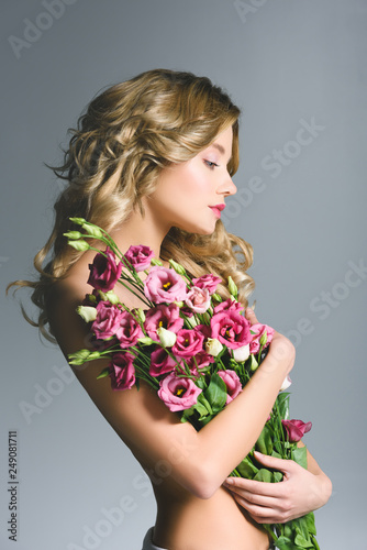 attractive woman holding bouquet of eustoma flowers isolated on grey