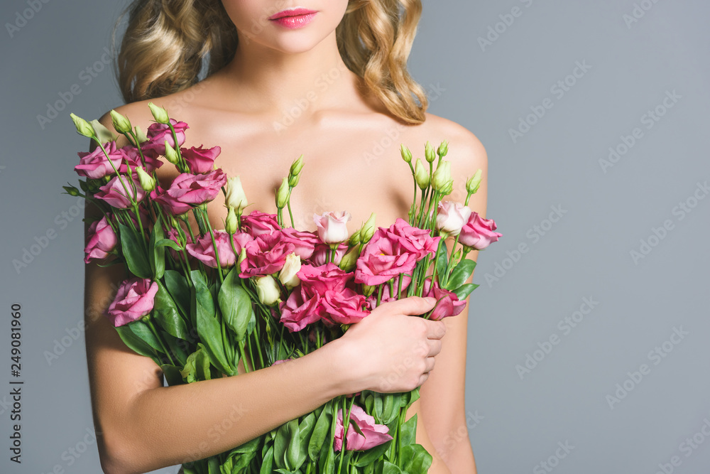 cropped view of naked woman holding bouquet of eustoma flowers isolated on grey