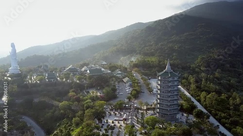 inspiring aerial panorama bouddhist complex with pagoda statue and roads lit by sun from behind green hills photo