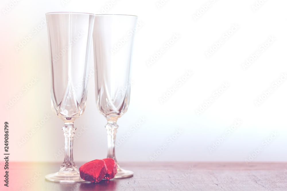 Obraz premium Two champagne glasses and two chocolate heart candies with copy space and vintage effect