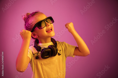 Neon portrait of young girl with headphones enjoying music. Lifestyle of young people, human emotions, childhood, happiness concept.