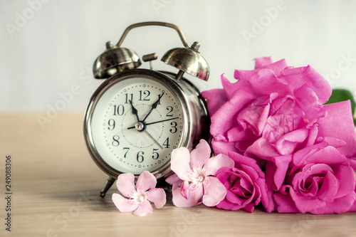 roses flower bouquet with clock on wooden table in vintage tone 
