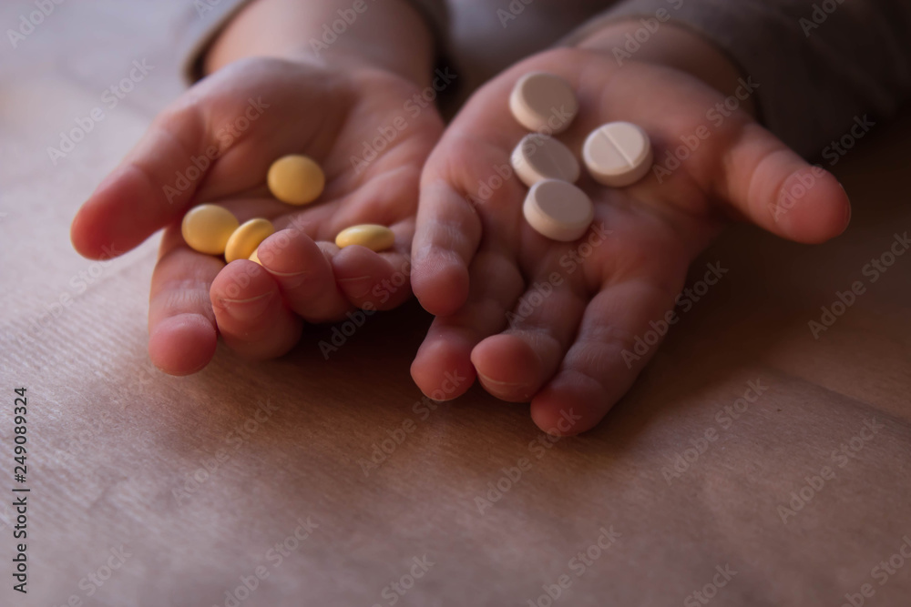 Baby hands with pills on paper background. Sick Child Has Medicine and Vitamins, Closeup, Neutral Background Baby hands with pills on paper background. Sick Child Has Medicine and Vitamins, Closeup, Neutral Background