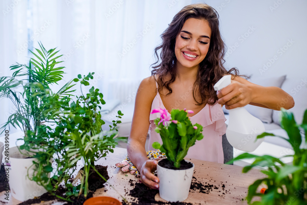 Young businesswoman sprays plants in flowerpots. Young businesswoman sprays plants in flowerpots.