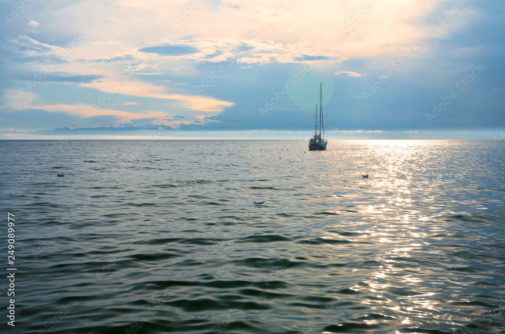 Beautiful sailing yacht on the horizon of Lake Baikal in summer at sunset