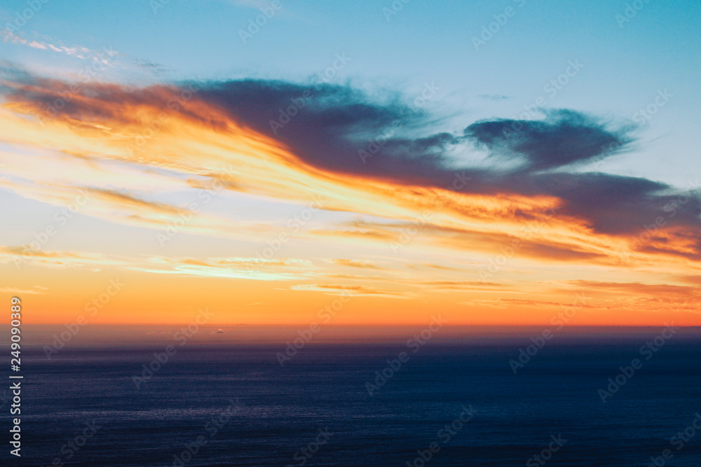 Background texture of dramatic cloud formations at sunset with an orange to purple gradient.