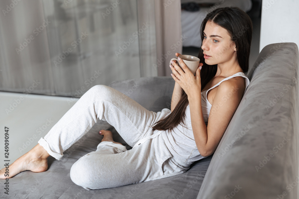 Fototapeta premium Beautiful young woman relaxing on a couch at home