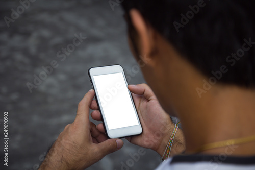 Man holding, touching or working on mobile phone with blank white screen with copy space. Male hands with touch screen smart phone closeup, working on device with clear screen. Technology concept.