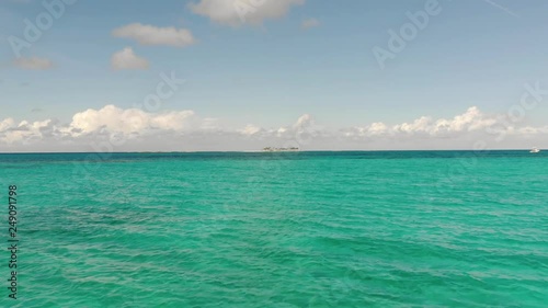 Rising up over beautiful blue sea in the Bahamas, Caribbean towards a small deserted island, pirate island, rose island, Aerial view photo