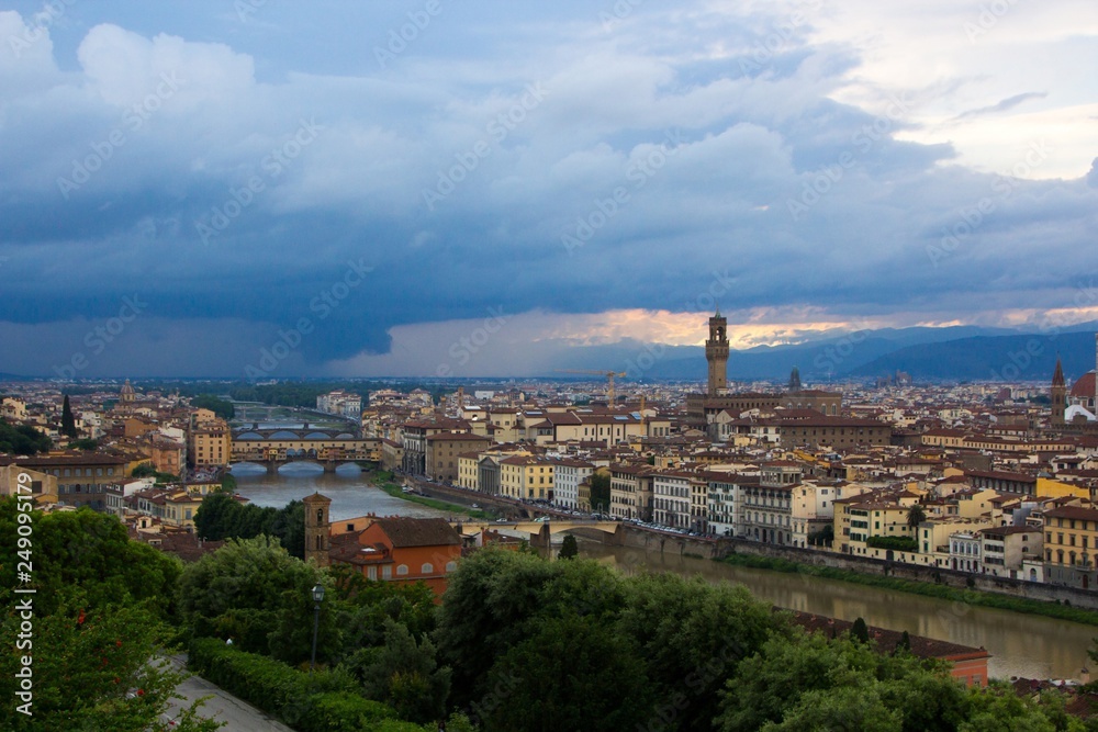 River Arno with bridge Ponte Vecchio and Palazzo Vecchio in the evening view from Piazzale Michelangelo. Dramatic sunset dark blue sky. Florence, Italy.