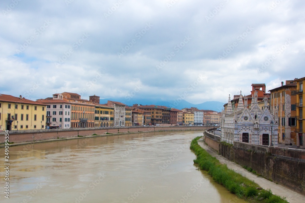 The Arno River and the small Gothic church of Santa Maria della Spina on the waterfront of Pisa. Cloudy, rainy weather. Pisa, Italy.