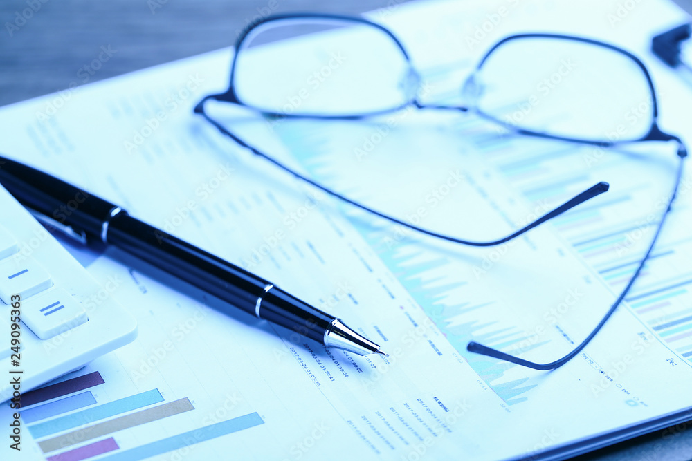 pen,glasses,calculator and business statistics on wooden table pen,glasses,calculator and business statistics on wooden table