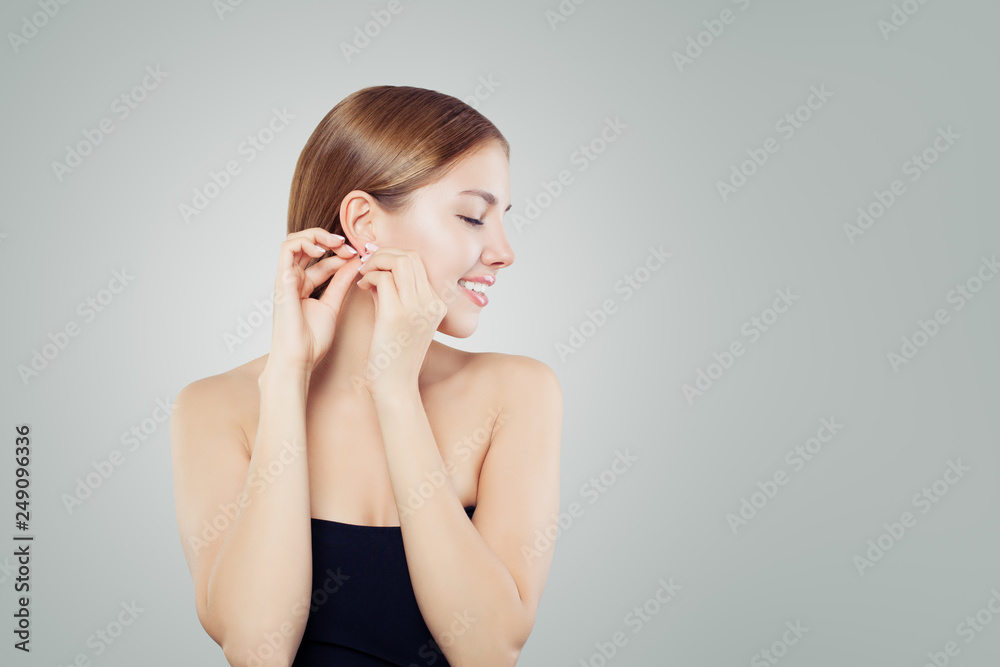 Model for earring jewelry. Cheerful woman puts on diamond earrings portrait Model for earring jewelry. Cheerful woman puts on diamond earrings portrait