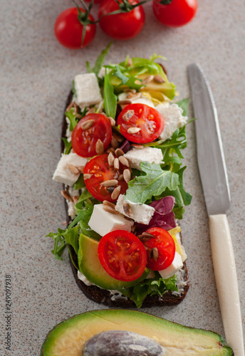 An avocado sandwich with tomatoes and cheeses. serving on the table	 photo