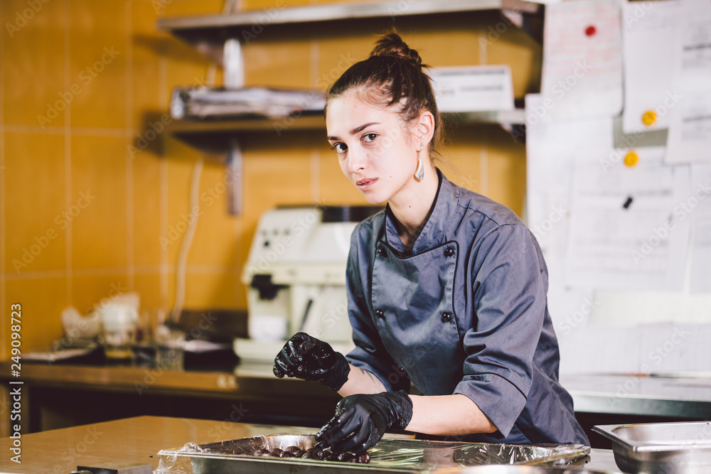Subject profession and cooking pastry. young Caucasian woman with tattoo of  pastry chef in kitchen of restaurant preparing round chocolate candies  handmade truffle in black gloves and uniform Stock Photo | Adobe