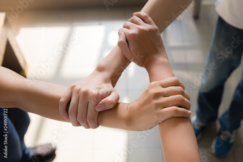 3 people are laying their hands together. They catch the wrist in a triangle in the daytime in Bangkok, Thailand. Concept, unity and collaboration