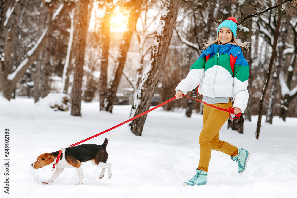 Young woman in winter park walking with her beagledog. Friendship, pet and human.