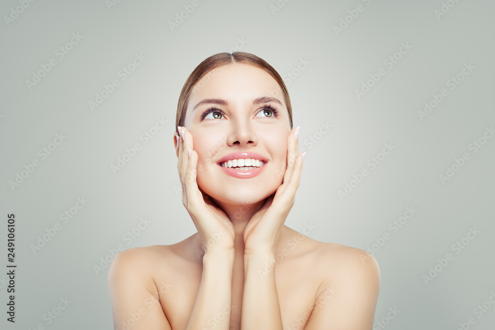 Spa woman smiling and looking up on background with copy space. Pretty girl with healthy clear skin. Facial treatment, skincare and cosmetology concept.