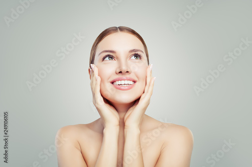 Spa woman smiling and looking up on background with copy space. Pretty girl with healthy clear skin. Facial treatment, skincare and cosmetology concept.
