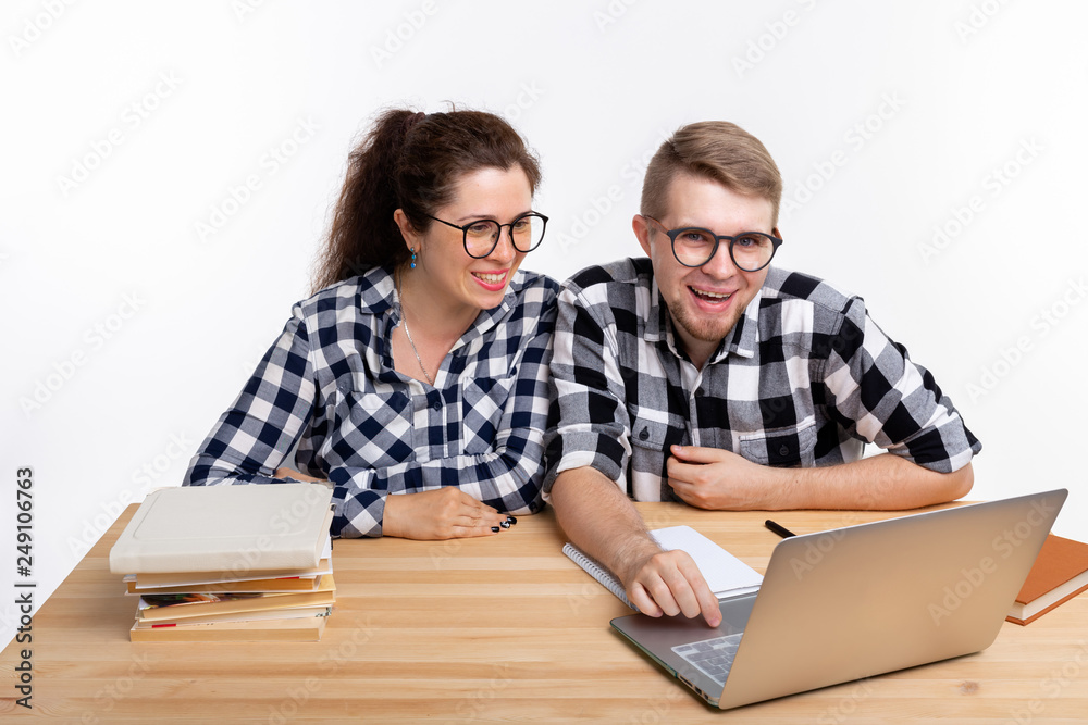 Nerds, geek, bespectacled and funny people concept - funny student couple in glasses sitting at the table Nerds, geek, bespectacled and funny people concept - funny student couple in glasses sitting at the table