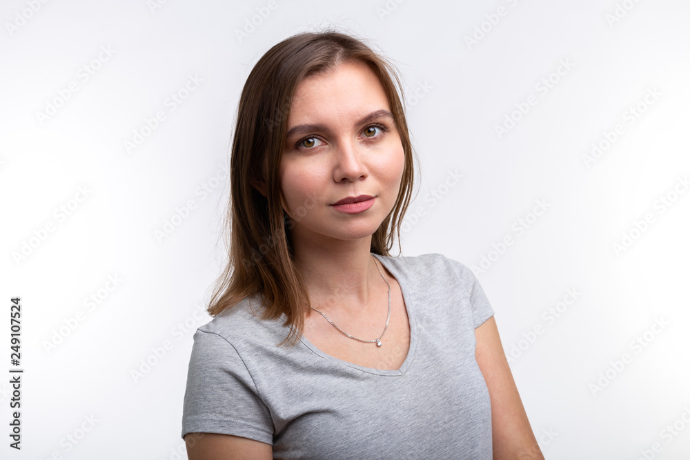 People and education concept - Close up portrait of lovely girl in grey shirt over white background People and education concept - Close up portrait of lovely girl in grey shirt over white background