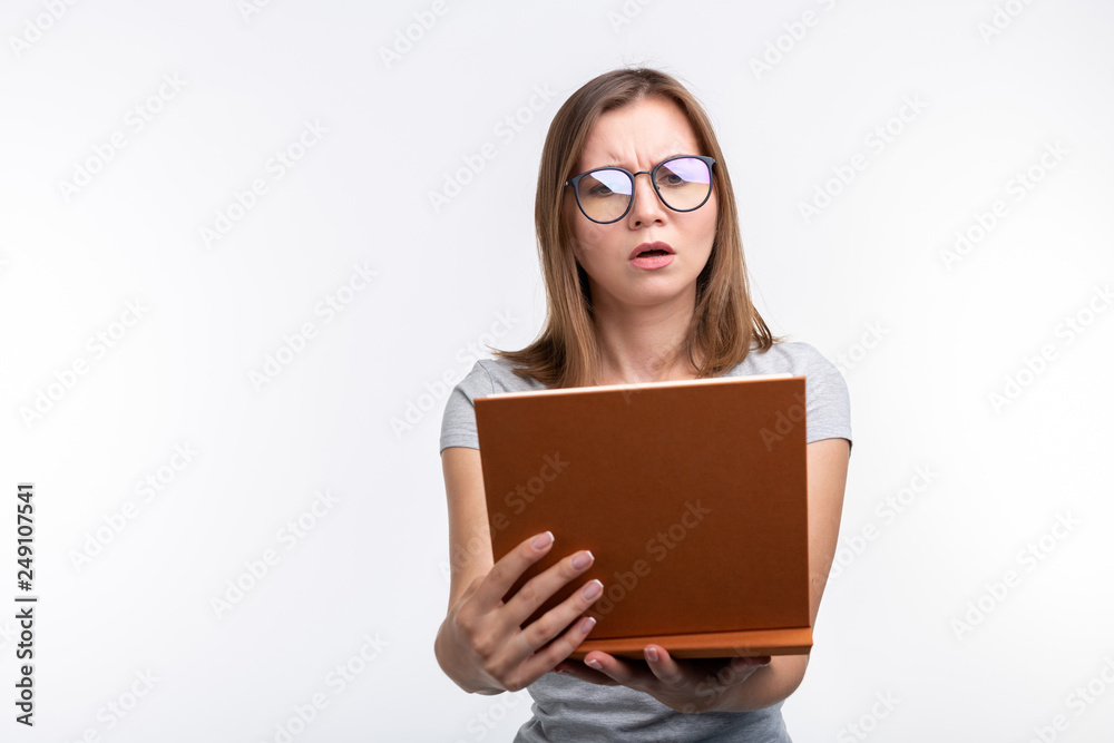 Study, education, people concept - female student is tired of learning classes, she is in gray shirt, standing with opened book Study, education, people concept - female student is tired of learning classes, she is in gray shirt, standing with opened book