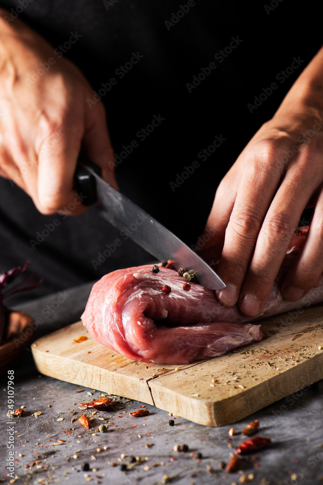 man cutting a piece of pork tenderloin