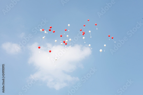 white and red ballons flying high in blue sky