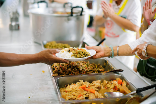 Volunteer food servers dish out a free charity : concept of helping