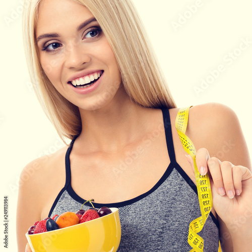 Woman in sportswear with tape measure and fruits