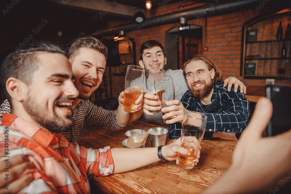 Long-awaited meeting of friends men. They drink beer in bar, take selfies